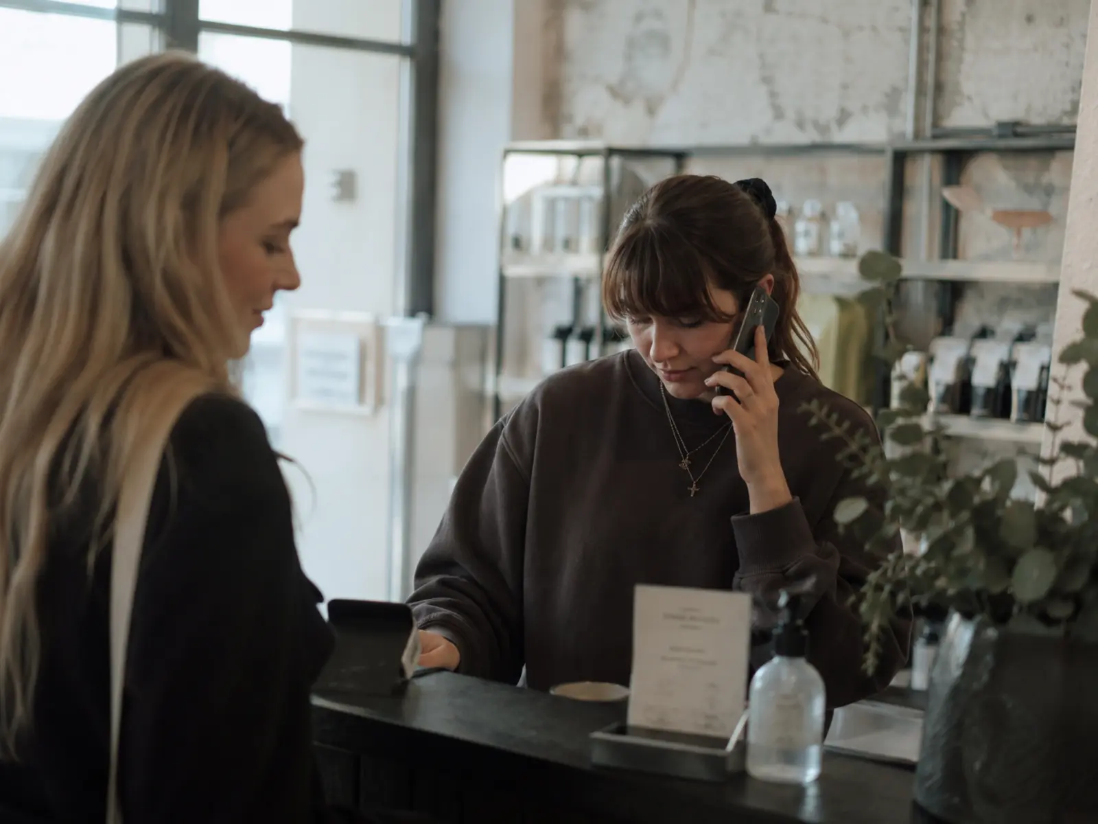 An Irish salon owner taking a booking on a phone at the counter