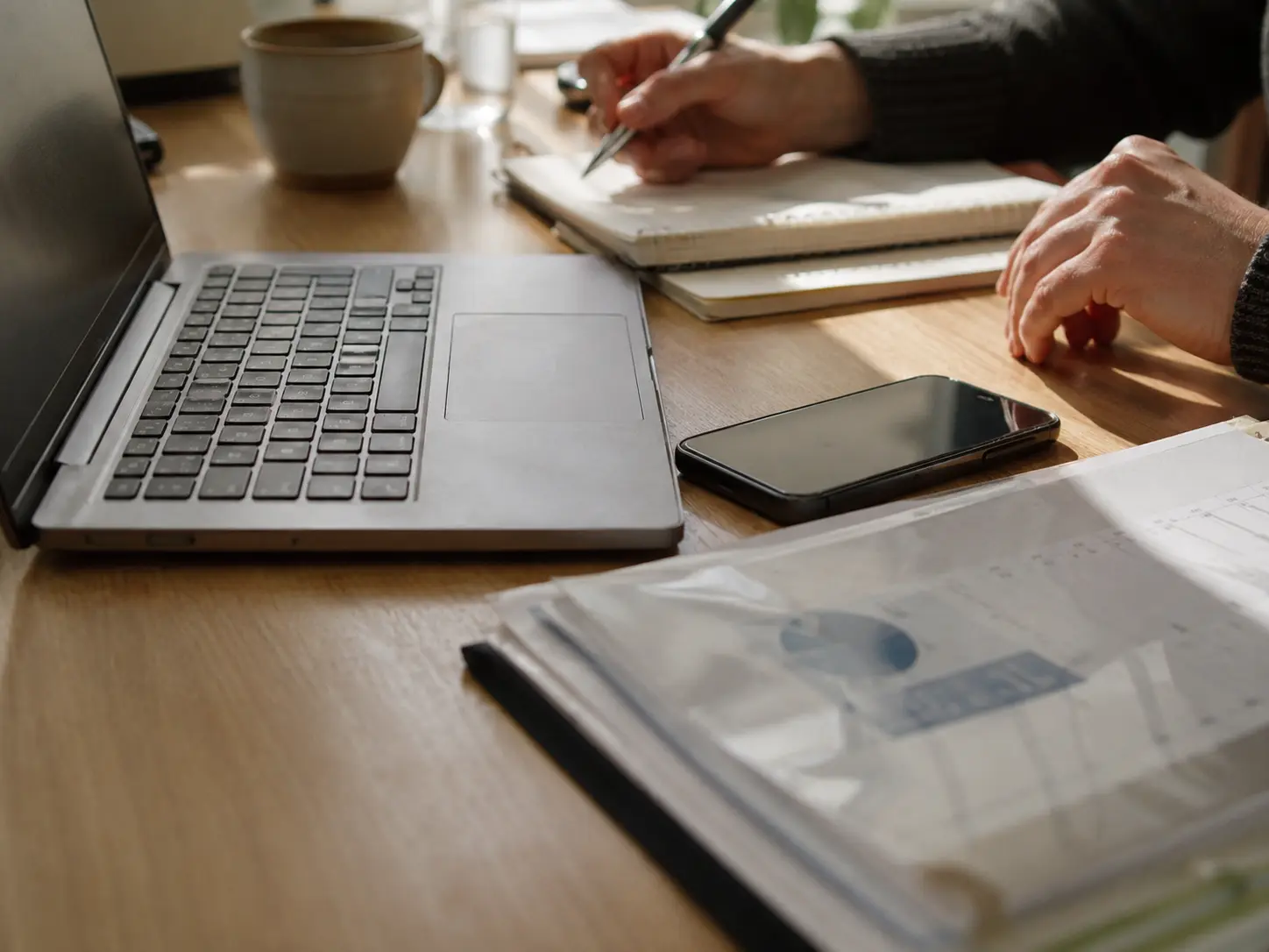 Laptop, phone and paperwork on a desk — connecting business tools