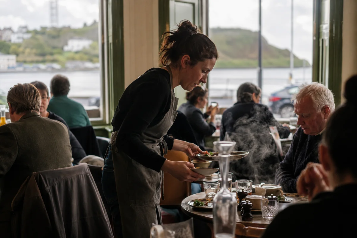A busy Irish café at service, a server clearing a table